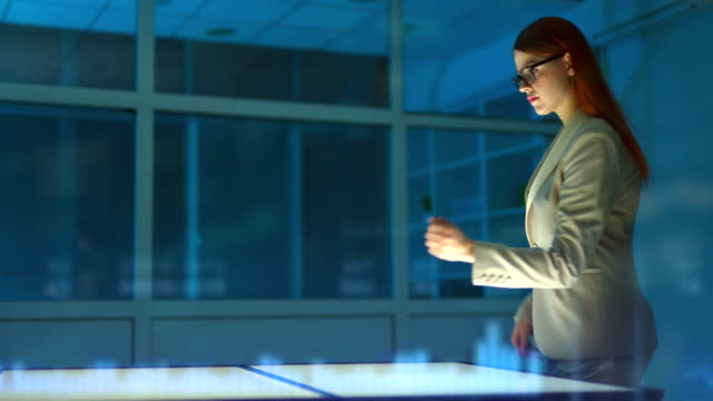 La-mujer-en-gafas-trabajando-con-una-pantalla-virtual-en-un-fondo-de-holograma