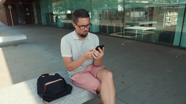 Hombre-sentado-con-smartphone-fuera.