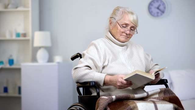 Upset-handicapped-woman-wearing-eyeglasses-reading-book,-loneliness-in-old-age