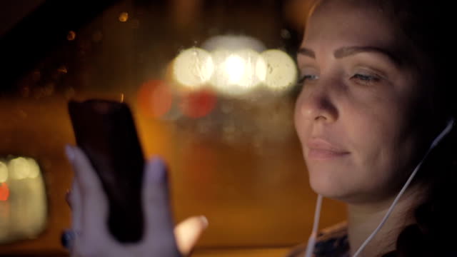 Portrait-of-young-beautiful-caucasian-woman-using-smart-phone-hand-hold-outdoor-in-the-city-night,-smiling,-face-illuminated-screenlight---social-network,-technology,-comunication-concept