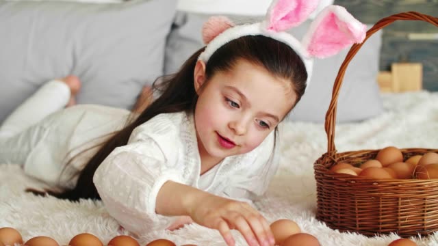 Chica-feliz-jugando-con-huevos-de-Pascua-en-la-cama