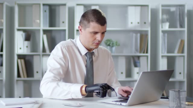 Hombre-de-negocios-con-brazo-protésico-mecanografía-en-Laptop