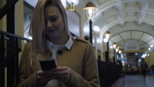 Eine-junge-schöne-Frau-arbeitet-auf-einem-Smartphone-in-einem-Flur