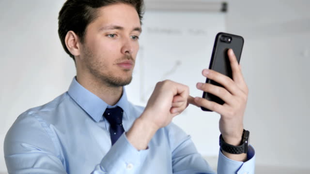 Junge-Geschäftsleute-mit-Smartphone-am-Arbeitsplatz-schließen
