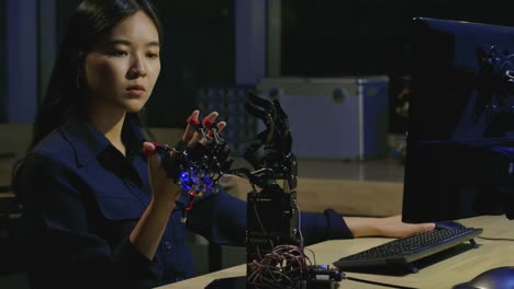 Junge-Elektronik-Entwicklungsingenieure-testen-innovative-Robotertechnologie-im-Labor.-Junge-asiatische-Frau-schafft-Bewegung-für-mechanische-Roboterhand.-Menschen-mit-Technologie--oder-Innovationskonzept.