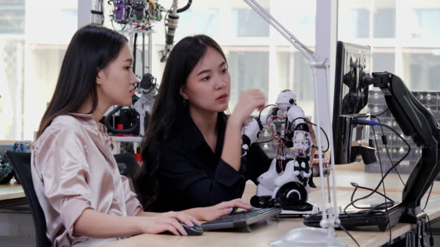 Un-joven-ingeniero-electrónico-asiático-trata-de-arreglar-el-robot-en-el-laboratorio.-Concepto-de-tecnología-e-innovación.