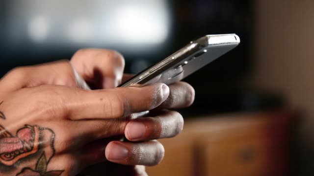 Männliche-tätowierte-Hand-tippen-auf-modernen-Smartphone