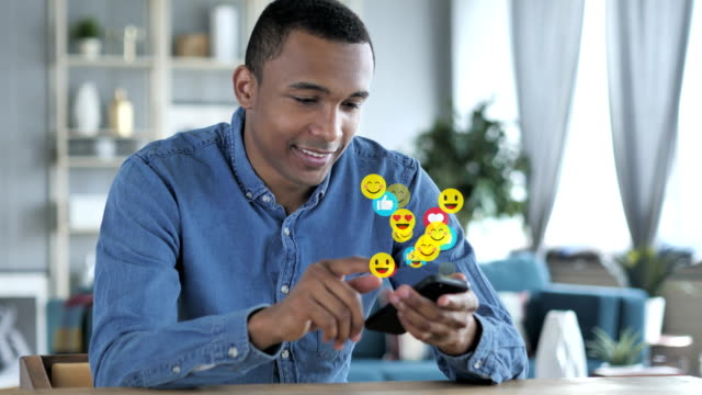 Glücklicher-afrikanischer-Mann-mit-Smartphone,-Emojis,-Smileys-und-Likes