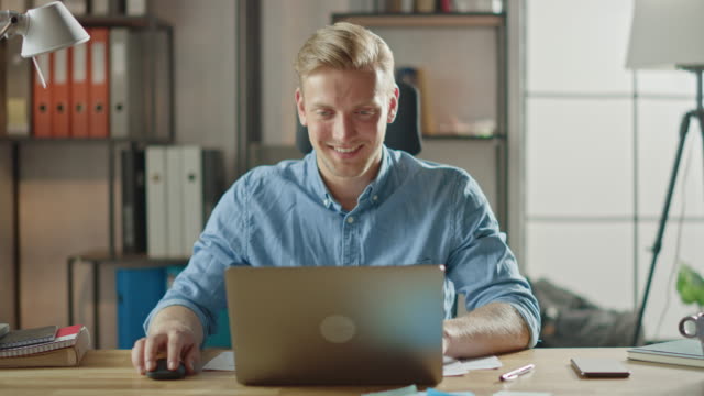 Handsome-Blonde-Geschäftsmann-sitzt-an-seinem-Schreibtisch-im-Büro-arbeitet-auf-einem-Laptop.-Kreativer-Unternehmer-mit-Computer-arbeiten-auf-Software-Unicorn-Startup-Project.-Student-Writing-Paper-für-die-Universität