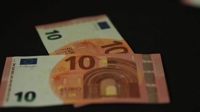 Banknoten-10-Euro-fallen-langsam-auf-den-schwarzen-Tisch.-Closeup.-zeitlupe