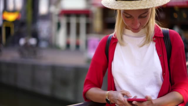 Positive-weibliche-Reisende-in-Hut-mit-Handy-für-Online-Chat-im-Roaming