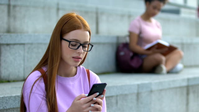 Traurige-kaukasische-weibliche-teen-in-Brille-Messaging-soziale-Netzwerke-auf-Handy