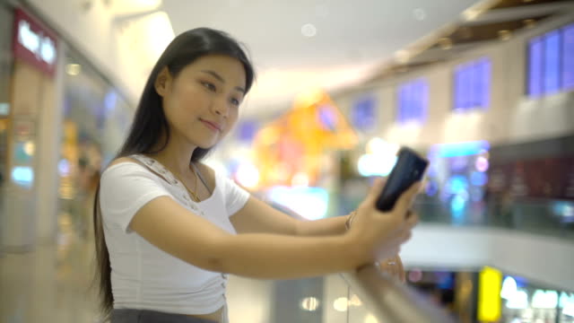 Lächelnde-asiatische-Frau-macht-Selfie-in-Einkaufszentrum