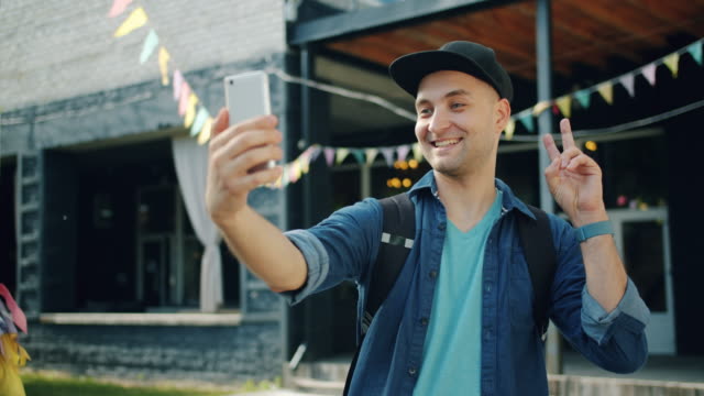 Cámara-lenta-de-hombre-alegre-tomando-selfie-al-aire-libre-usando-la-cámara-del-teléfono-inteligente