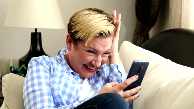 Woman-with-smart-phone-laughing-at-the-home
