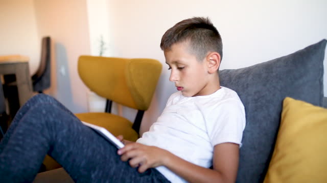 Young-boy-is-playing-games-on-his-tablet-at-home