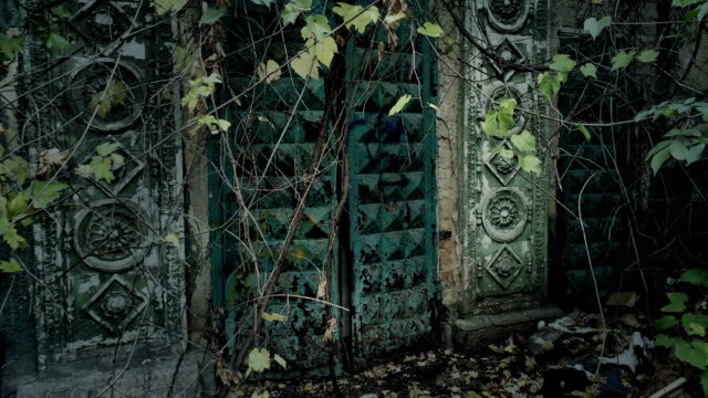 Abandoned-ancient-building-with-ornamental-gateway-decoration-in-woods-leaves