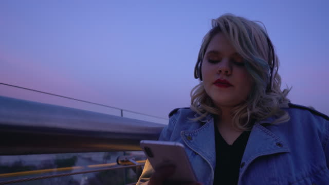 Inspired-woman-enjoying-music-in-earphones,-browsing-social-media-on-gadget