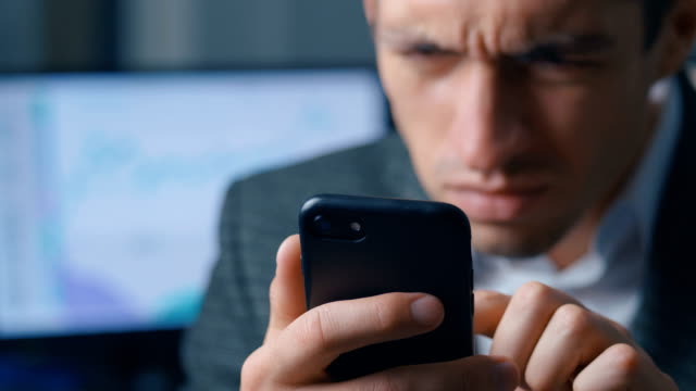 Close-up-of-a-successful-businessman-in-a-suit-is-using-a-smartphone-in-the-office-at-the-workplace.-Man-uses-the-application-on-a-mobile-phone,-office-on-the-background