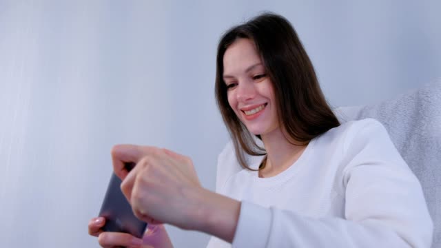 Young-brunette-woman-is-playing-game-on-mobile-phone.