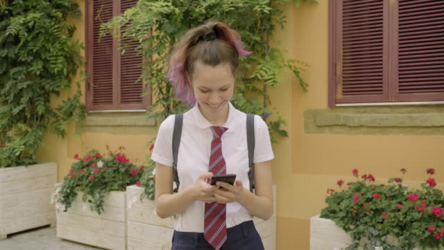Schöne-Student-Teenager-Mädchen-mit-Smartphone-lesen-und-schreiben-Textnachricht,-lächelnd-auf-der-Stadtstraße