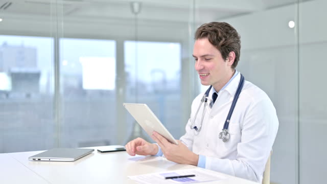 Attraktive-junge-männliche-Arzt-tun-Video-Chat-auf-Tablet