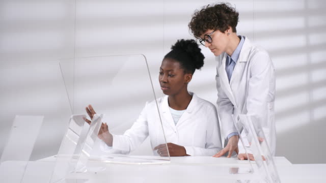 Multiethnische-Wissenschaftlerinnen-mit-Blick-auf-futuristischen-AR-Touchscreen-im-Labor