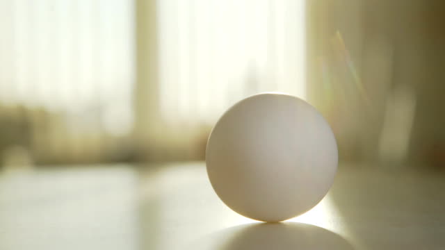 Huevo-gira-sobre-la-mesa:-mano-hace-girar-un-huevo,-primero-vuelve-rápidamente