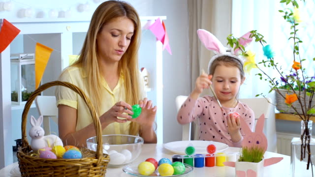 ¡Feliz-Pascua-de-resurrección!-Madre-y-su-pequeña-hija-con-divertidas-orejas-de-conejo-para-colorear-huevos-de-Pascua