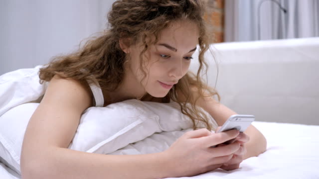 Frau-im-Bett-mit-Telefon-für-Surfen-im-Internet