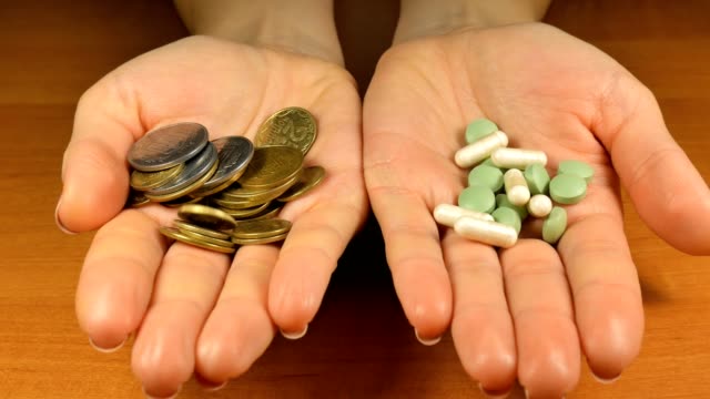 Las-mujeres-con-dinero-y-pastillas-en-las-manos-que-le-ofrece-elegir-para-la-salud