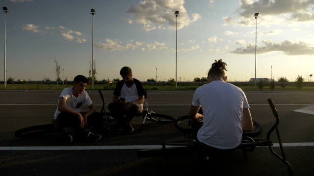 Young-bikers-friends-relaxing-after-training-lying-down-and-using-their-smartphones-addicted-to-smart-technology