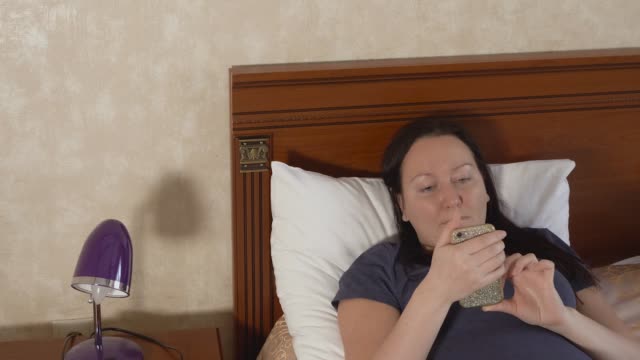 Erwachsene-Frau-auf-Bett-liegend-und-social-Media-im-Handy-Surfen