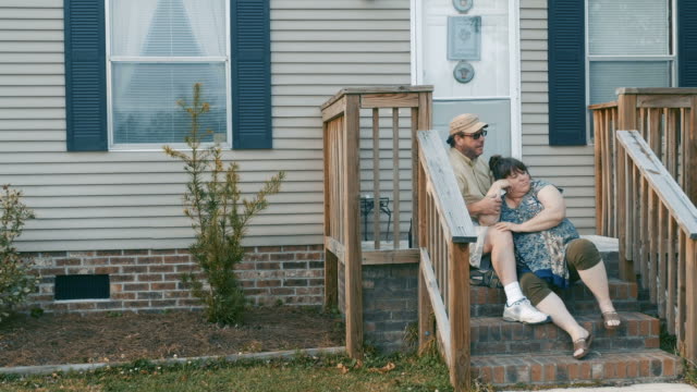 A-plus-size-couple-sitting-on-their-porch-steps-in-suburbia