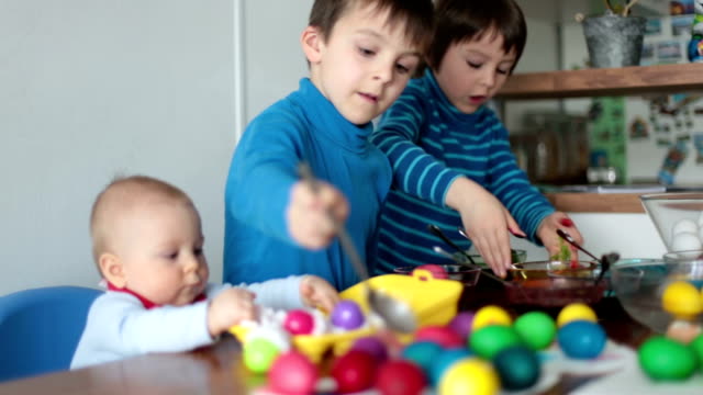 Drei-Kinder,-Brüder,-färben-und-Bemalen-von-Ostereiern-zu-Hause-in-der-Küche-für-den-Urlaub