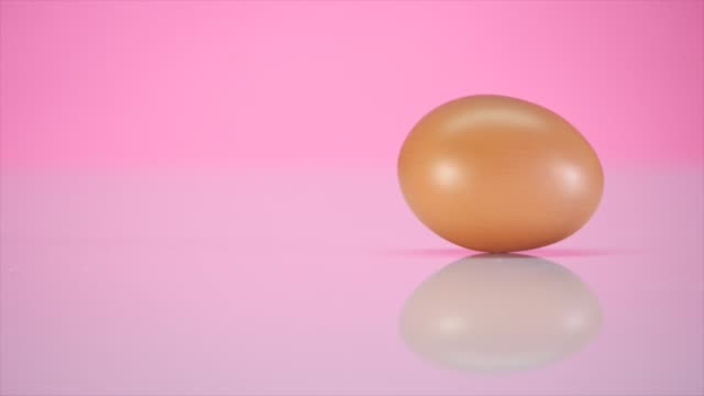 Das-Ei-dreht-sich-auf-einem-Tisch-auf-einem-rosa-Hintergrund