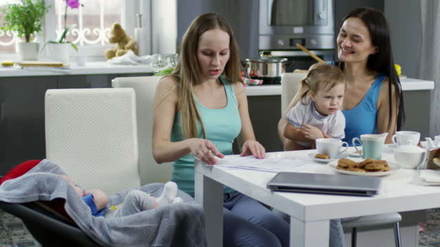 Female-Couple-with-Children-Filling-Documents-at-Home