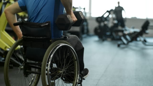 Irreconocible-hombre-en-silla-de-ruedas-haciendo-filas-de-un-brazo