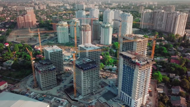 Aerial-drone-shot.-Construction-of-high-rise-buildings-in-the-developing-area-of-a-large-city.-In-the-picture,-construction-cranes-and-many-houses-under-construction.-Around-the-construction-site-to-the-right