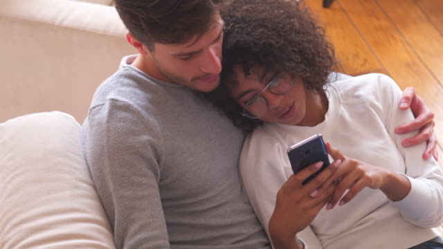 Relaxed-couple-using-mobile-phone-at-home