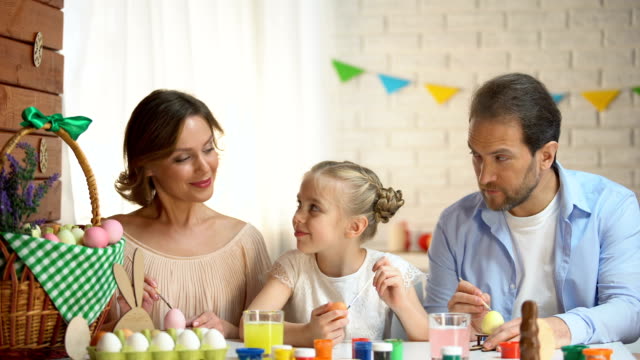 Happy-family-looking-into-camera-and-smiling,-coloring-eggs,-Easter-preparation