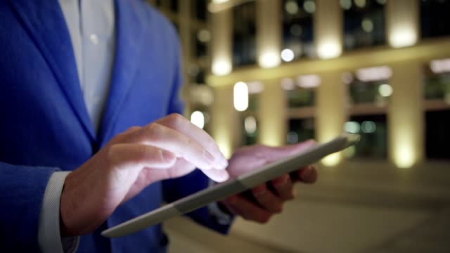 Close-up-Hände-unkenntlich-Geschäftsmann-mit-Anwendung-auf-digitale-Tablet-im-Freien-bei-Nacht