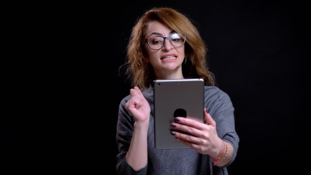 Closeup-portrait-of-attractive-caucasian-middle-aged-woman-having-a-video-call-on-the-tablet-casually-with-the-background-isolated-on-black
