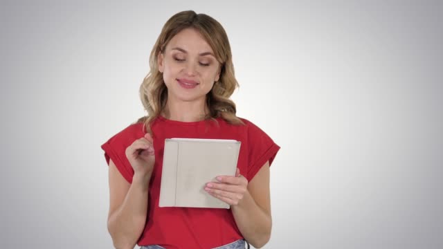 Smiling-woman-with-tablet-computer-presenting-turning-pages-on-gradient-background