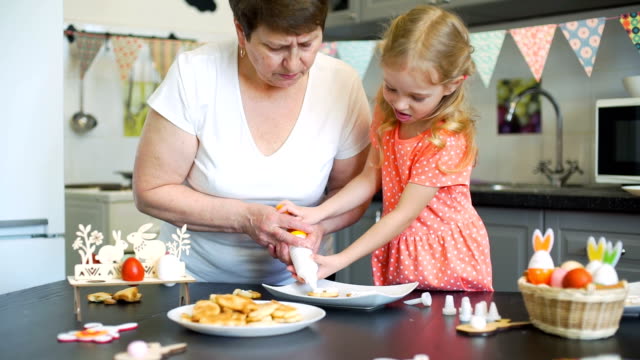 Little-Girl-with-Grandma-Putting-Cream-on-Cookies