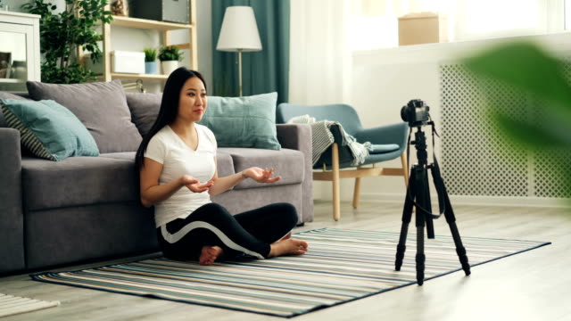 Fröhliche-asiatische-Frau-populäre-Bloggerin-ist-die-Aufnahme-von-Video-mit-professioneller-Kamera-im-Gespräch,-dann-zeigen-Daumen-nach-oben-und-winkende-Hand-auf-ihre-Anhänger.-Vlogging-und-Technologiekonzept.