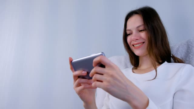 Young-brunette-woman-is-playing-game-on-mobile-phone.
