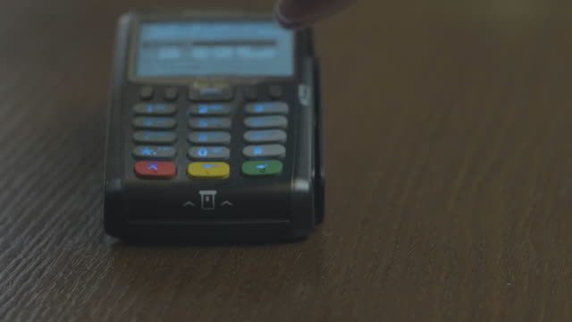 Closeup-shot-of-customer-pay-over-the-wireless-tradings-card-reader.-Adult-human-hands-of-businessman-use-bankcard:-leans,-entering-password-to-withdraw-funds-then-hold-and-sliding.-Noncash-payments.