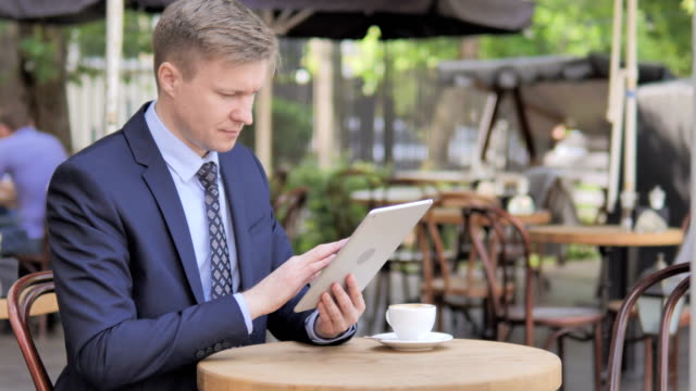 Geschäftsmann-nutzt-Tablet,-Sitting-im-Außencafé