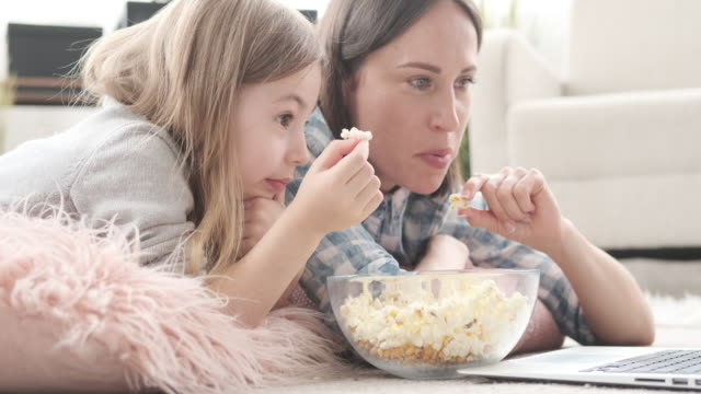 Mutter-mit-Tochter,-die-Popcorn-isst,-während-sie-Film-sieht